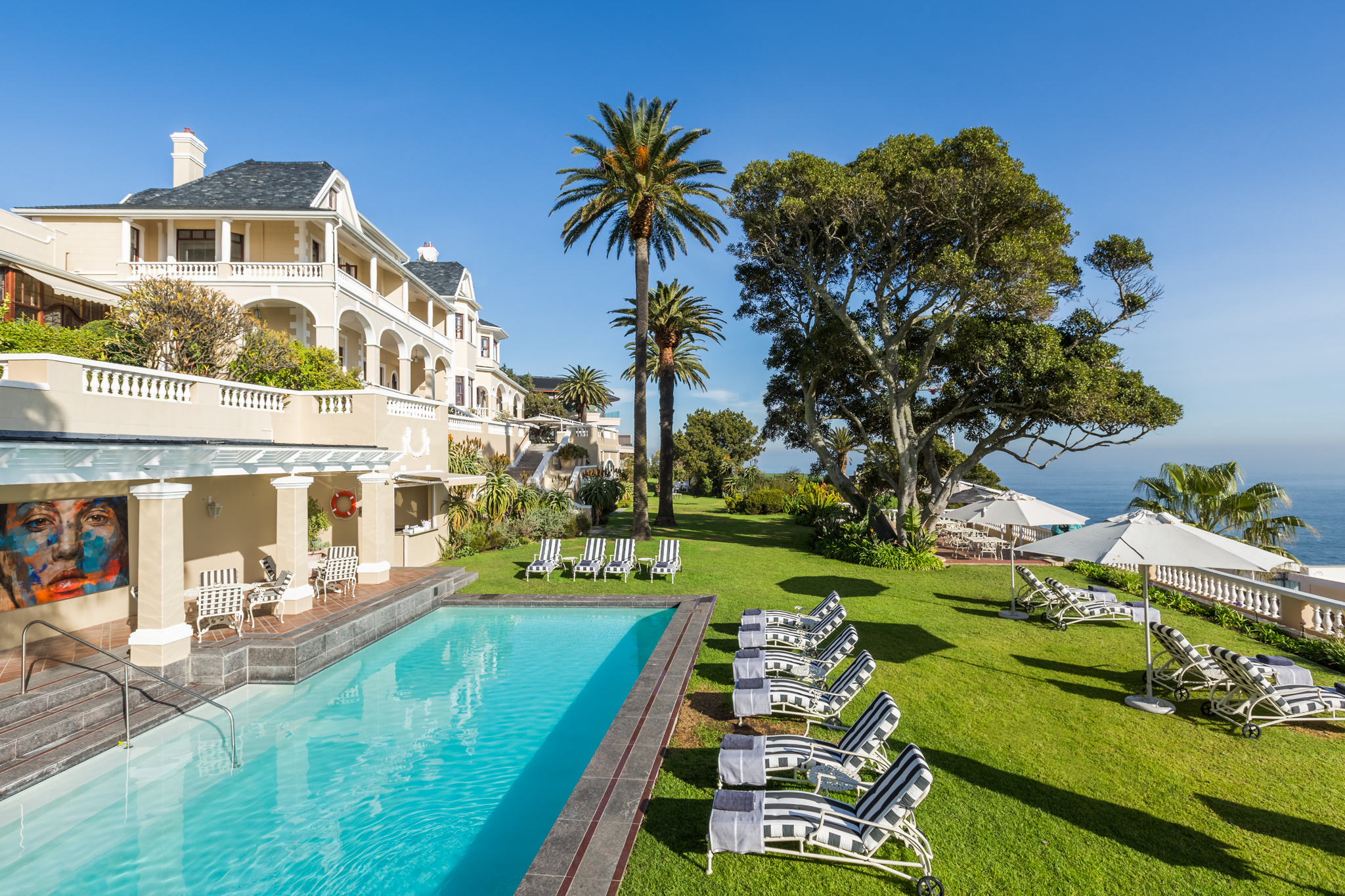 ellerman-house-garden-exterior A luxurious cliffside hotel with elegant architecture, lush gardens, and a sparkling pool overlooks the Atlantic Ocean - an exquisite setting for a babymoon safari.