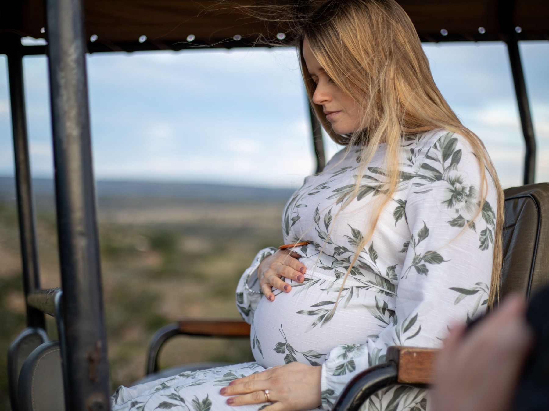 luxury-safaris-with-rhino-africa-at-amakhala_D6A0837 Katharina sits in an open safari vehicle, cradling her baby bump while gazing out at the vast African wilderness during her babymoon safari.